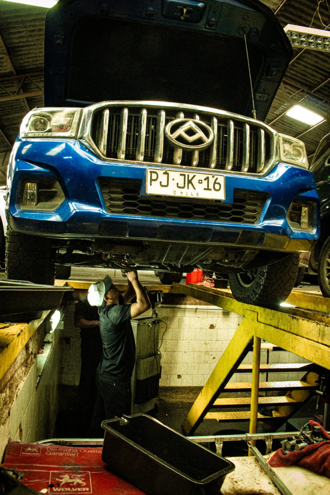 Camioneta azul sobre el elevador del taller